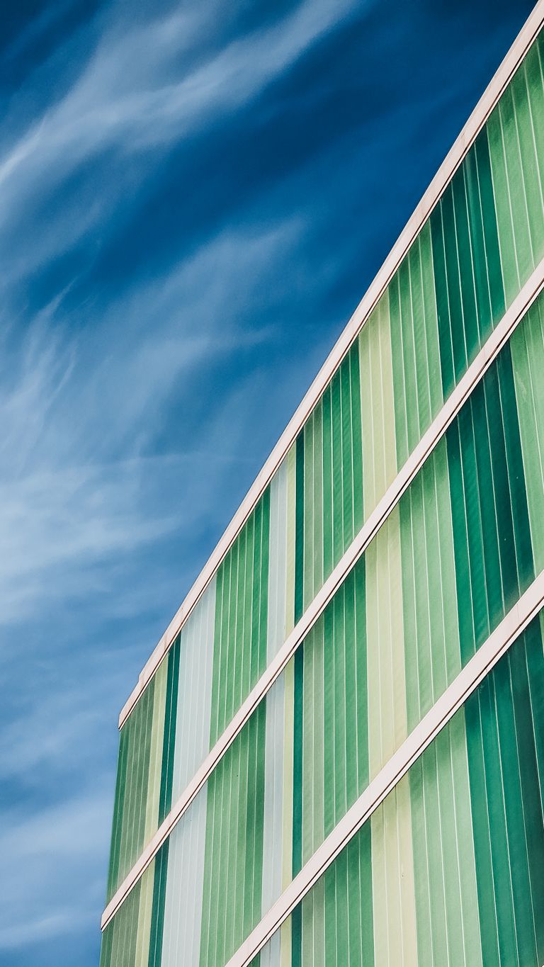 Abstract view of a modern green building facade with a clear blue sky.